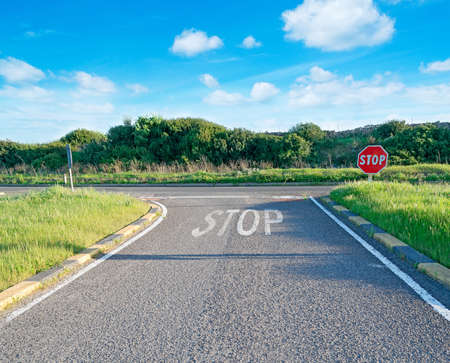 country road with stop sign under a cloudy skyの写真素材