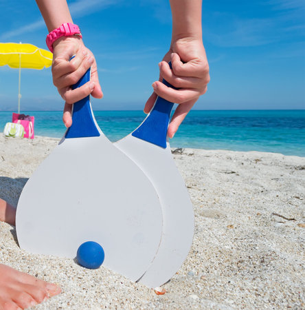 girl taking two beach rackets stuck in the sandの写真素材