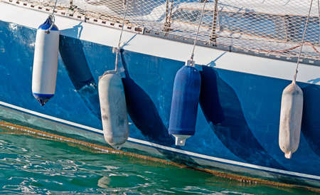 four boat fenders on a blue hullの写真素材