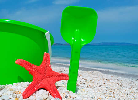 green bucket and red starfish by the shore in Sardiniaの写真素材