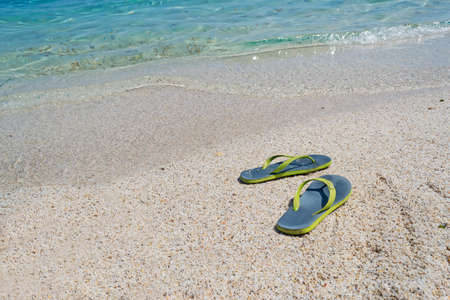 flip flops by the foreshore with turquoise waterの写真素材