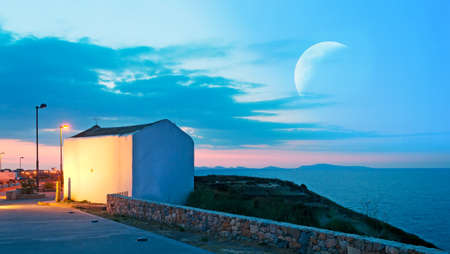 small white church at dusk under a huge moonの写真素材