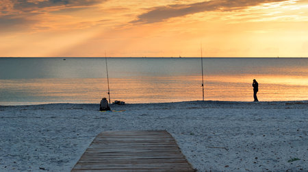 two people fishing at sunsetの写真素材