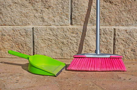 green shovel and pink broom on the groundの写真素材
