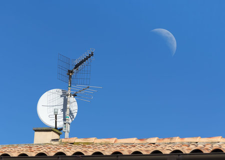 tv antenna on a house roof under the moonの写真素材