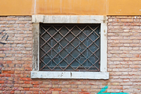 old grilled window in a brick wall in Venice, Italy