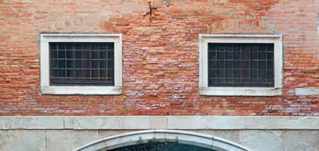 two grilled windows in a brick wall