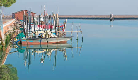boats and trees reflected in Venice lagoonの写真素材