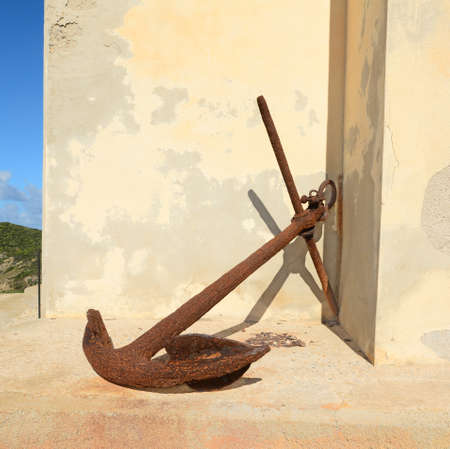 old anchor leaned against a beige wallの写真素材