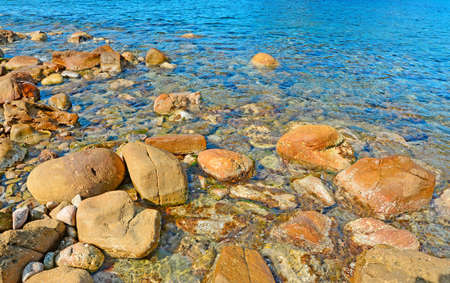 brown rocks and blue sea in Porticciolo, Sardiniaの写真素材