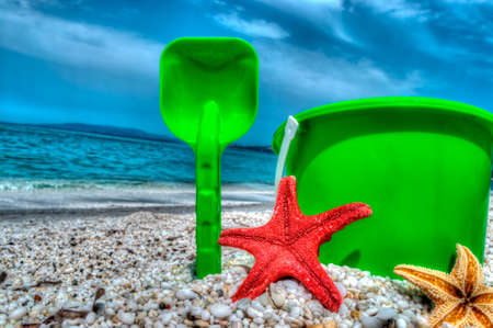 shovel, bucket and starfish on a pebbled shoreの写真素材