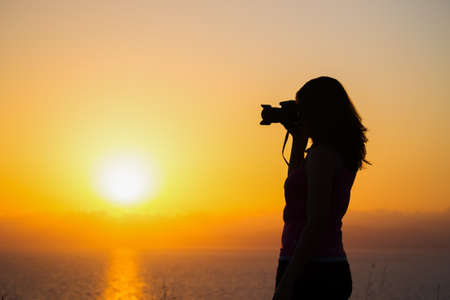 female photographer silhouette at duskの写真素材