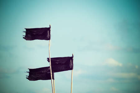 three black flags under a blue skyの写真素材