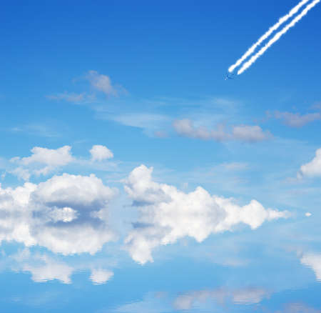 cloudy sky with airplane reflected in the waterの写真素材