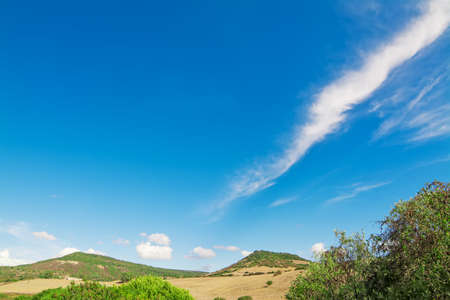 green hills and blue sky with clouds on a sunny day in Alghero, Sardiniaの写真素材