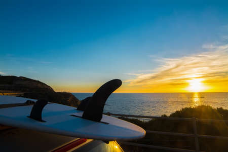 surfboard on a car rooftop at sunsetの写真素材