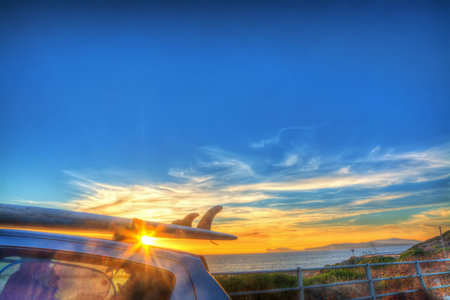surfboard on a car rooftop at sunset