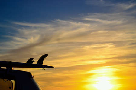 car with surfboard by the sea at sunsetの写真素材