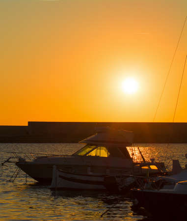 boat silhouettes in Alghero harbor at sunsetの写真素材