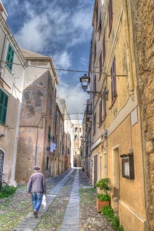old man walking in a old street in Alghero old town. Processed for hdr tone mapping effectの写真素材