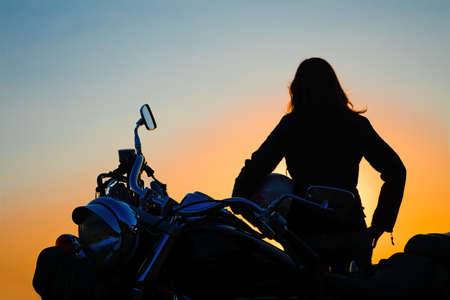 classic motorcycle and girl silhouette at duskの写真素材