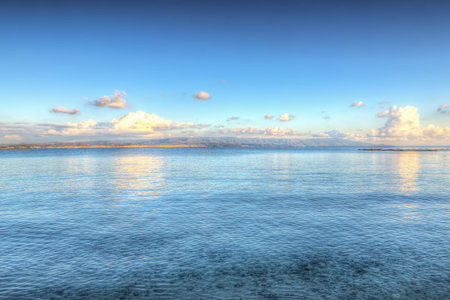 white clouds reflected in the water at sunset. Shot in Lazzareto beach, Sardinia.