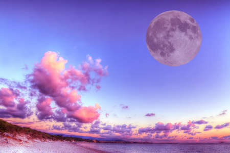 huge moon over a pink shore at sunset. Processed for hdr tone mapping effect.の写真素材