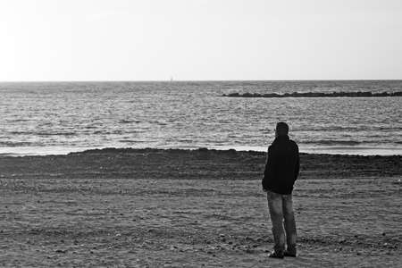 man alone at the beach in winter. Black and white shotの写真素材