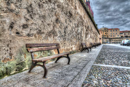 row of wooden benches in Alghero harbor.の写真素材