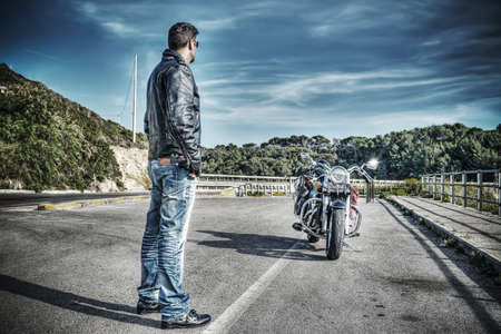 biker standing next to a classic motorcycle in hdr tone mapping effectの写真素材