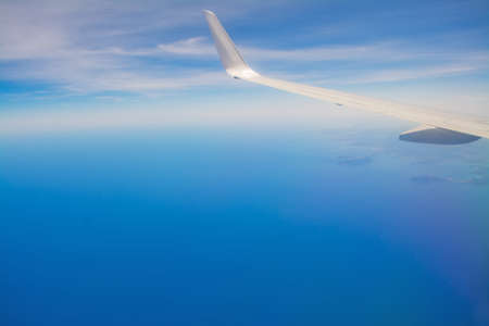 white airplane wing over a blue sky and seaの写真素材