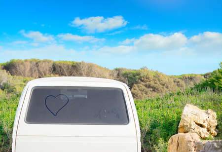 heart drawn on a dirty back window on a summer dayの写真素材