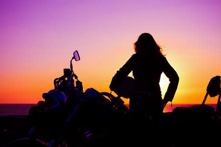 biker girl and classic motorcycle at sunsetの写真素材