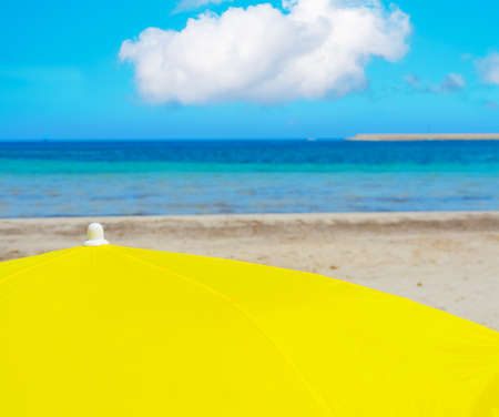 yellow parasol under a cloudy sky in Alghero, Sardiniaの写真素材