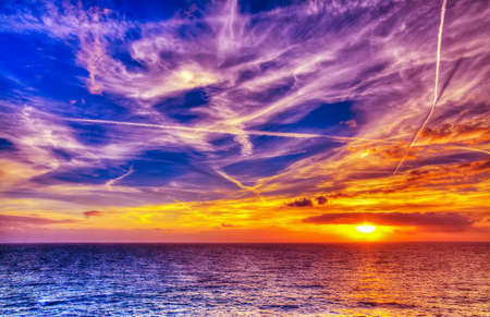 bright sun and white clouds over the sea in Alghero coastline at sunset, Sardiniaの写真素材