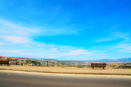 bench on the edge of the road under a blue skyの写真素材