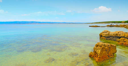 rocks and sand in Alghero shoreline, Italyの写真素材