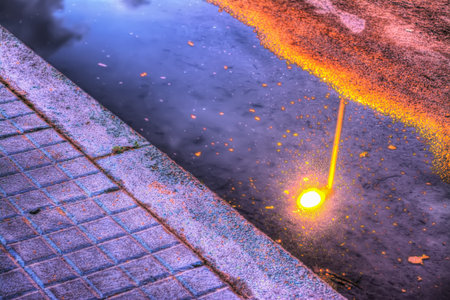 bright lamppost refelcted in a puddle at sunsetの写真素材