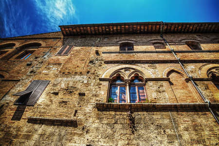 typical building in San Gimignano under a blue sky with clouds, Italyの写真素材