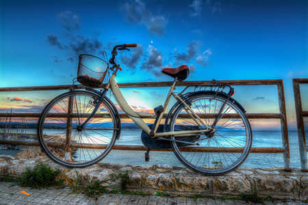 old bike leaning on a balustrade by the seaの写真素材