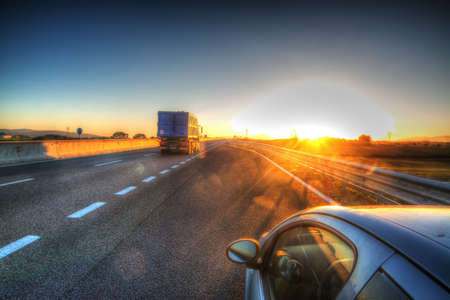 car and truck on a country road at sunsetの写真素材