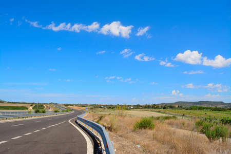 guard rail in a country road under cloudsの写真素材