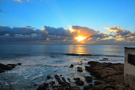orange and blue sky over Alghero rocky shore at sunset, Italyの写真素材