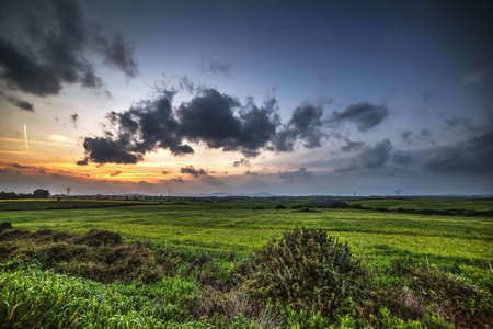 dark clouds over a green field at sunsetの写真素材