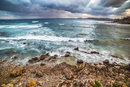 Alghero coastline under a dramatic sky at sunset, Italyの写真素材