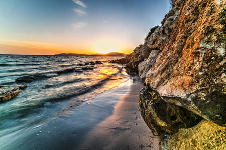 rocks and sand in Alghero shore at sunset, Sardiniaの写真素材