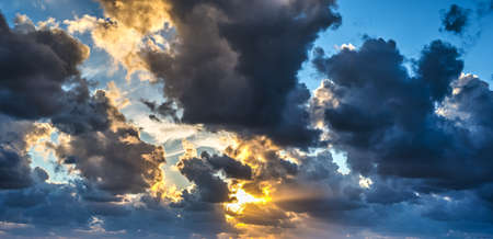 dark clouds and bright sun at sunsetの写真素材