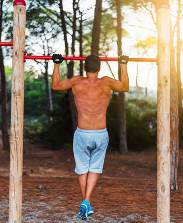 man doing pull ups in a park at sunsetの写真素材