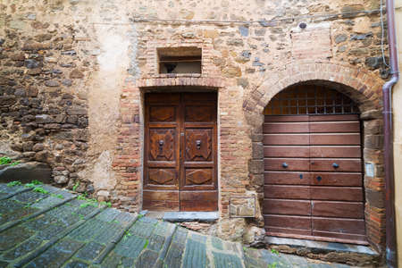 wooden doors in a rustic wall in Montalcino, Tuscanyの写真素材