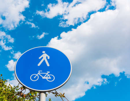 Pedestrian and bike sign under a cloudy sky in Sardiniaの写真素材